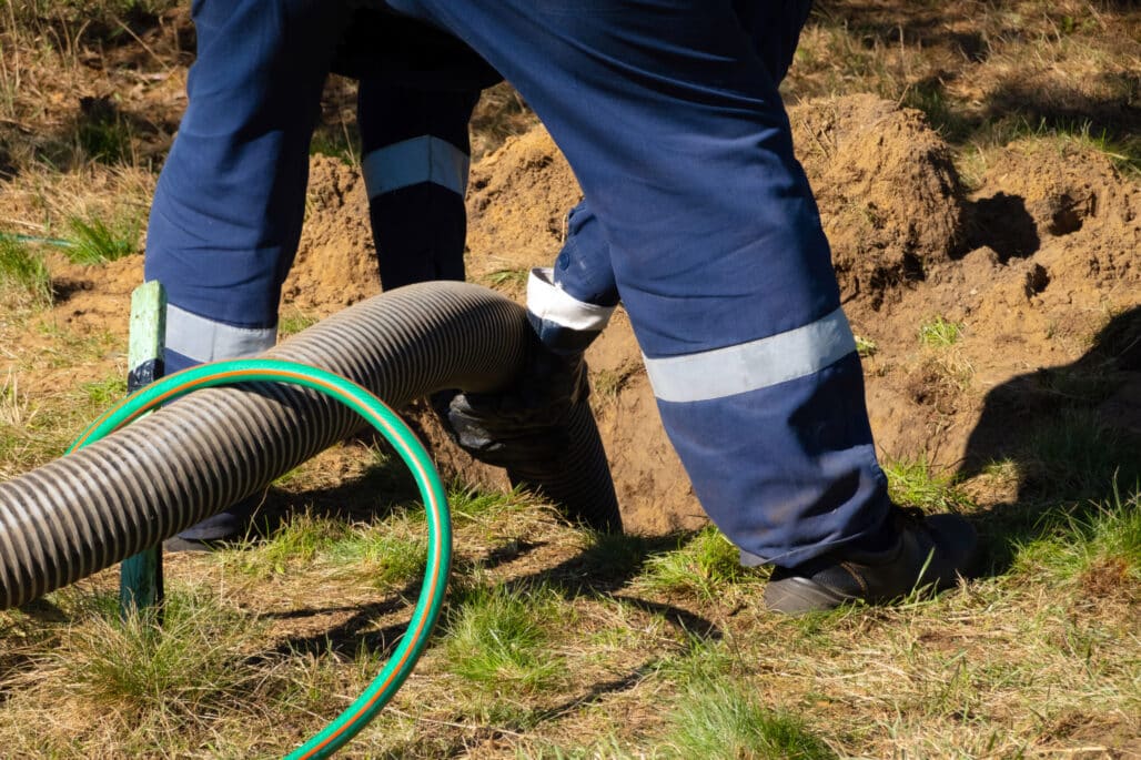 worker holding pipe, providing septic cleaning service